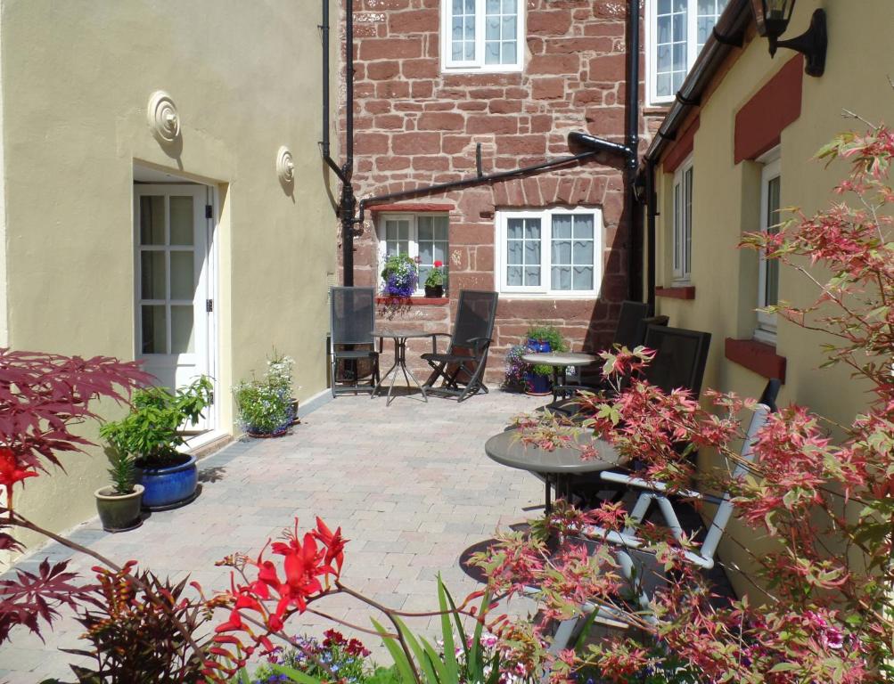 Barrowgarth Guest House في أبليبي: فناء به طاولة وزهور أمام مبنى