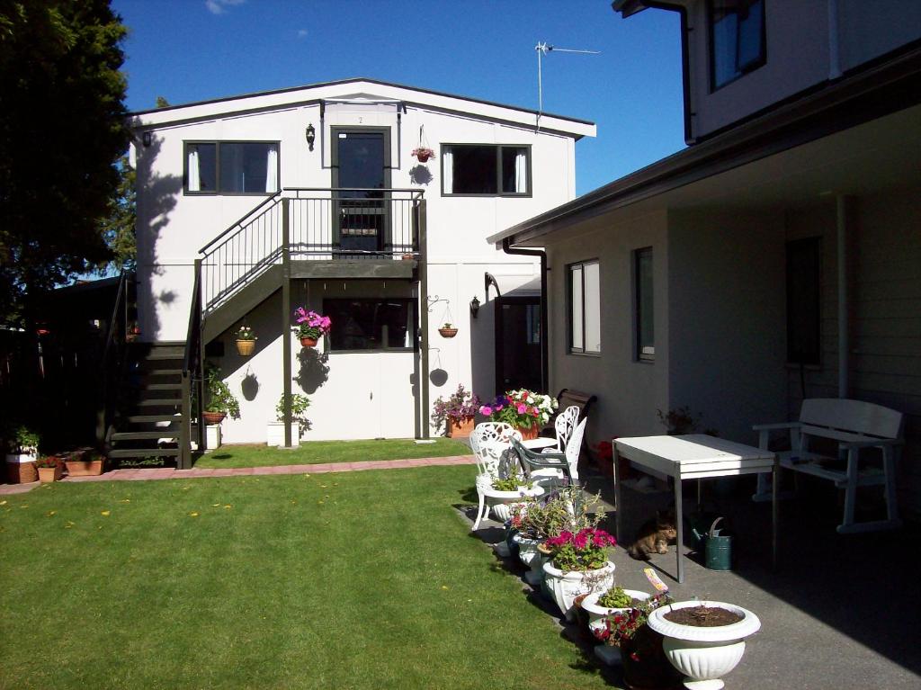 Casa blanca con patio con sillas y flores en Stream View en Christchurch