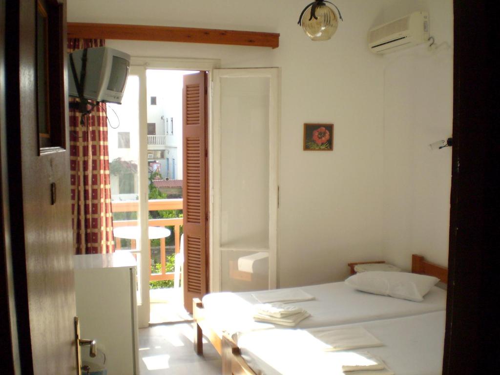 a white room with a bed and a balcony at Hotel Maroulis in Naxos Chora