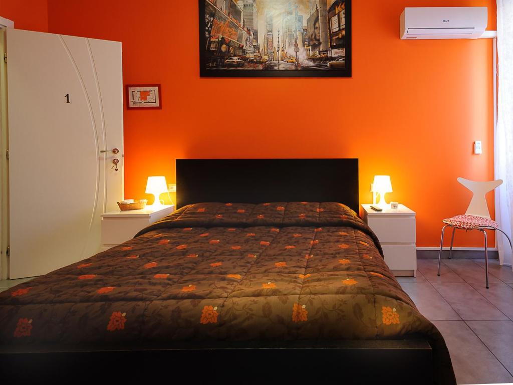 a bedroom with a bed with an orange wall at Adriatic Room I in Ciampino