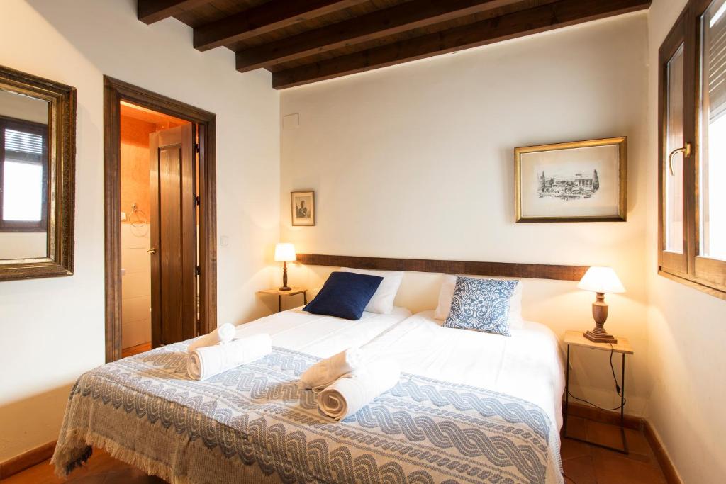 1 dormitorio con 1 cama blanca grande con almohadas azules en Apartamento Puerta Elvira Centro, en Granada