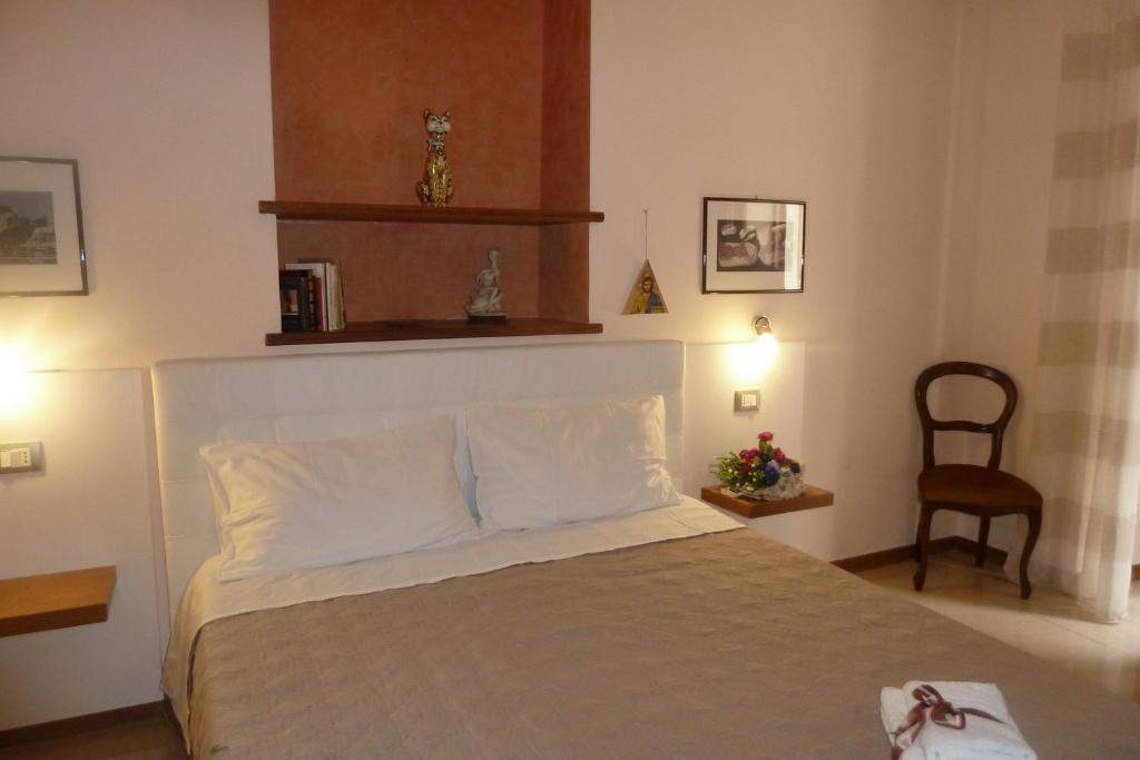 a bedroom with a bed with white pillows and a chair at Casa Vico Romano 2 in Taormina