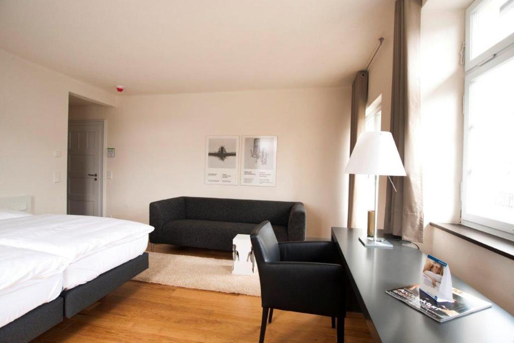 - une chambre avec un lit, un canapé et un bureau dans l'établissement Villa Behr, à Wendlingen am Neckar