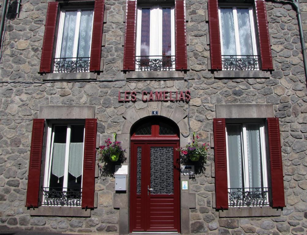 ein Steingebäude mit roten Türen und Fenstern in der Unterkunft Les Camélias in Le Mont-Dore