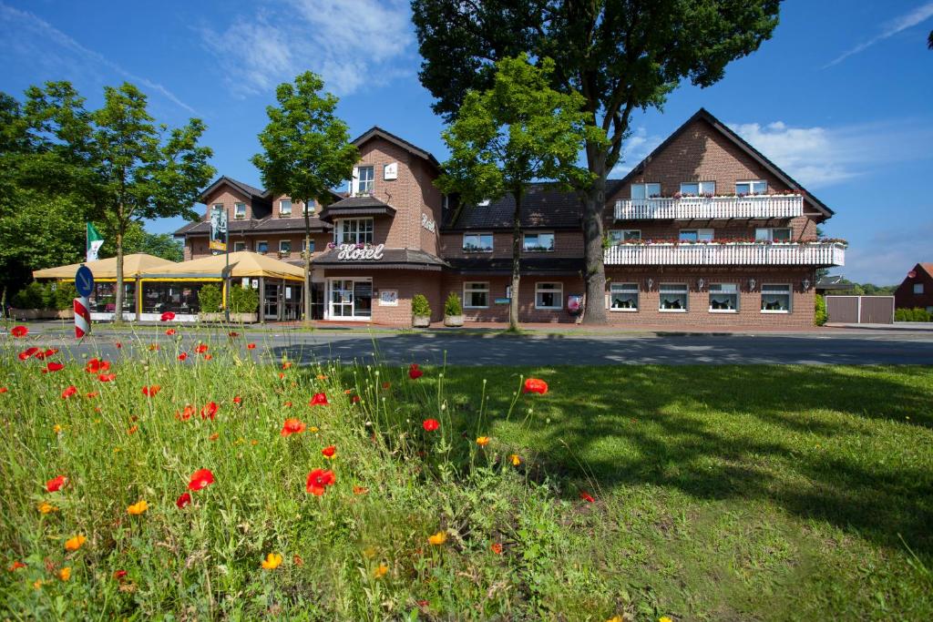 a building with a field of flowers in front of it at Hotel Bügener in Gronau