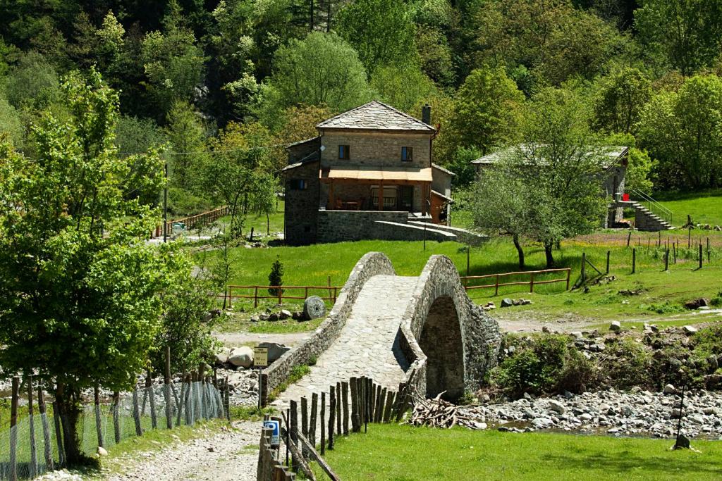 une maison au milieu d'un champ avec un pont en pierre dans l'établissement Agriturismo Mulino Marghen - Restored WaterMill - Retreat Center, à Zeri