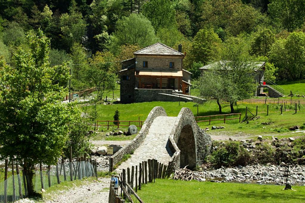 a house in the middle of a field with a stone bridge at Mulino Marghen - Agriturismo e Retreat Center in Zeri