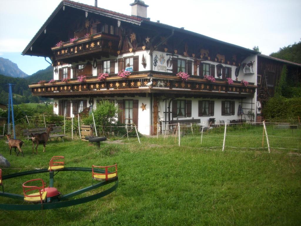 ein großes Haus auf einem Feld mit Tieren davor in der Unterkunft Weinfeldhof in Berchtesgaden