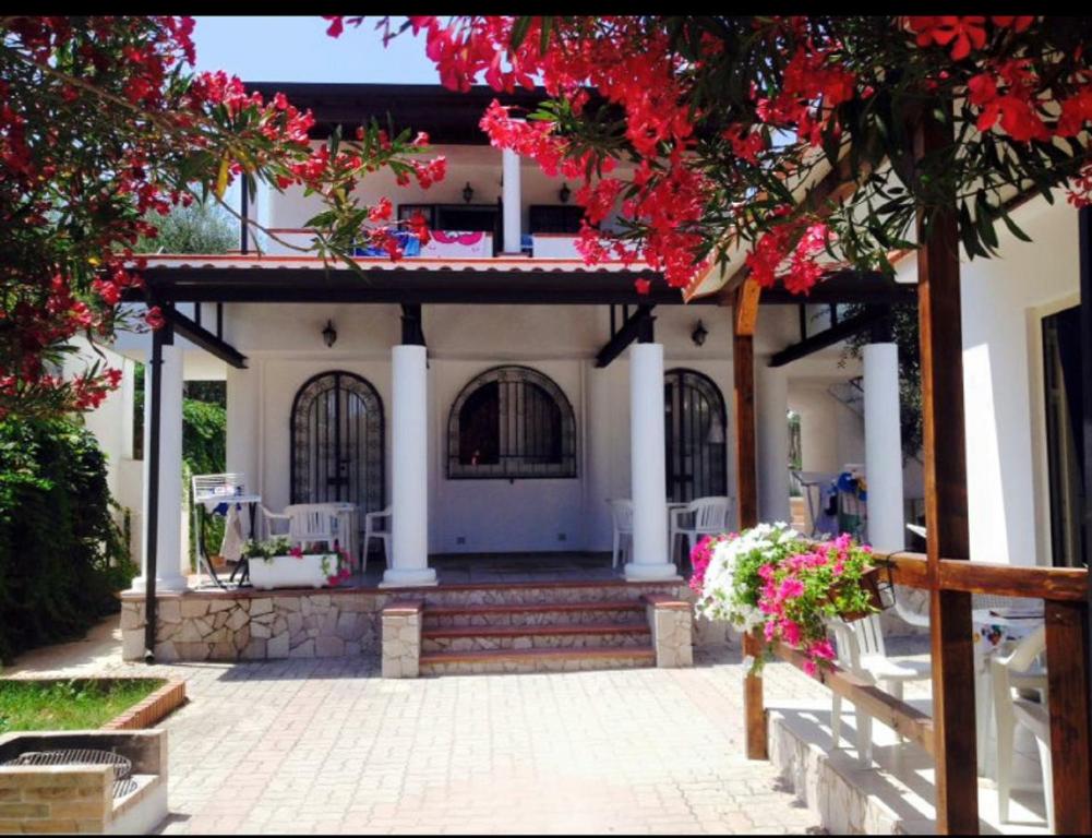 a white house with a porch with red flowers at Villa Bianca in Peschici