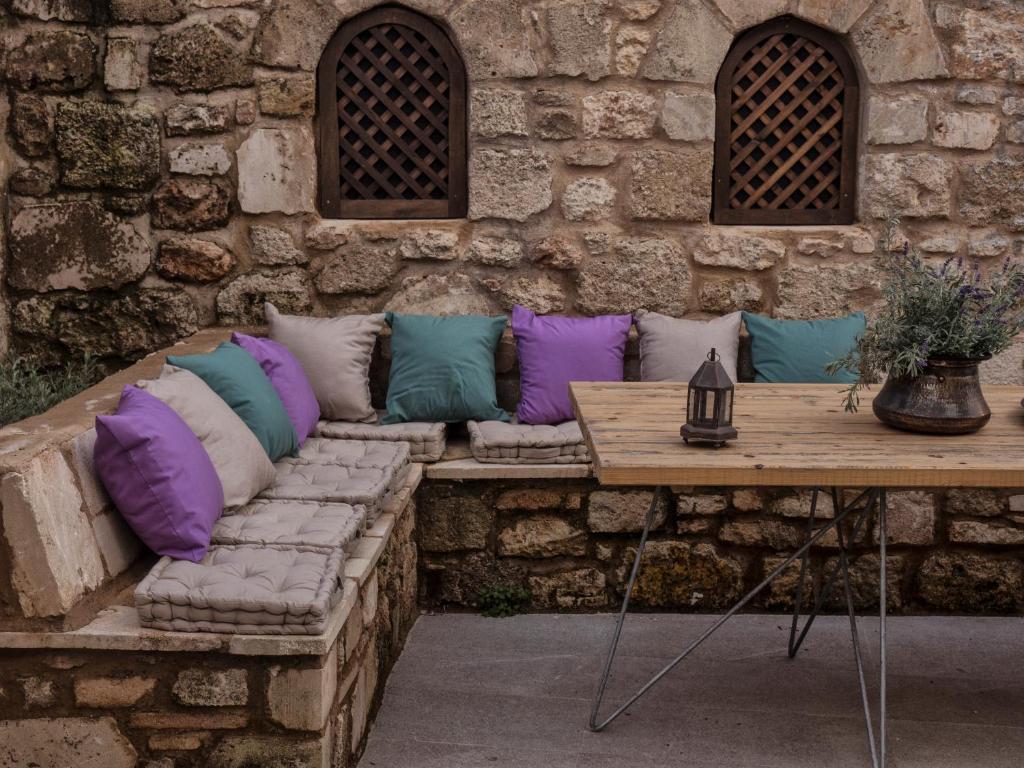 a stone wall with a couch with colorful pillows at Trinity Boutique Hotel in Rhodes Town