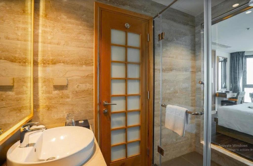 A marble-look bathroom contains a vessel sink and glass-enclosed shower.