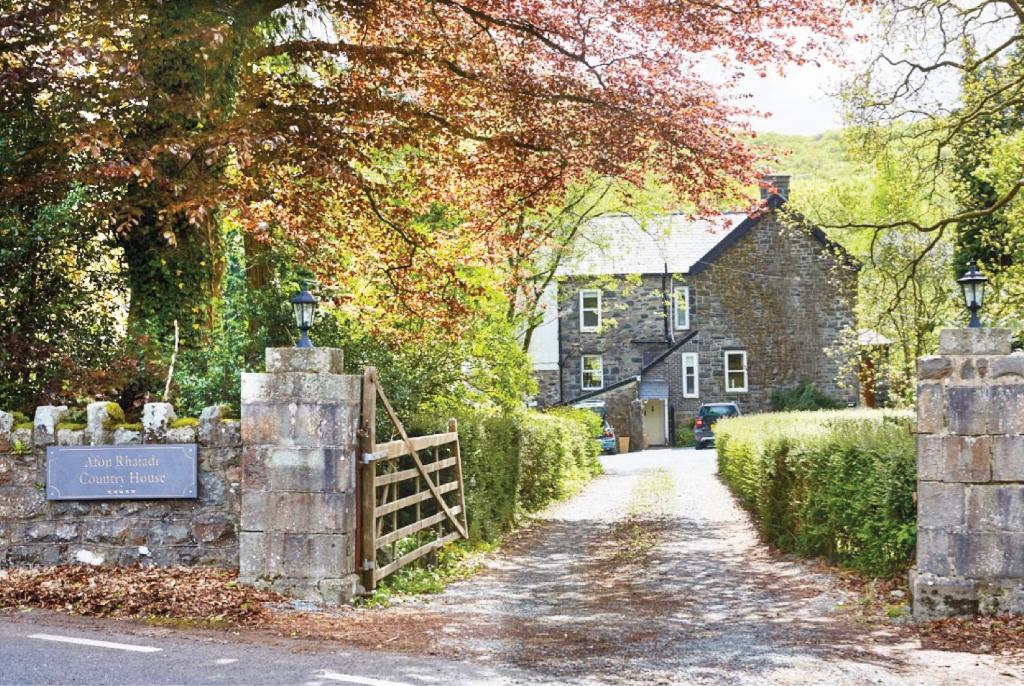 a house with a fence and a gate in front of a street at Afon Rhaiadr Country House in Dolgellau