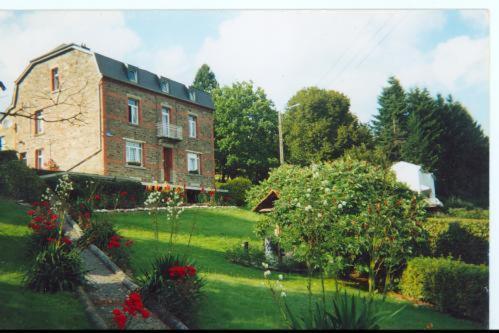 un gran edificio de ladrillo con un jardín delante de él en Villa Louise, en Bouillon