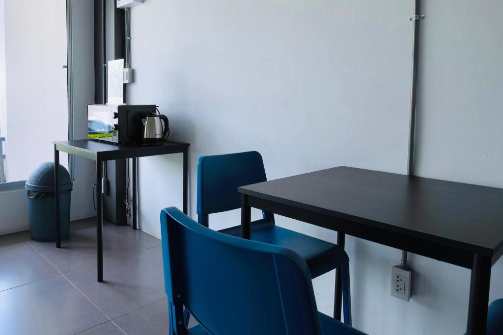 A compact dining and work corner with two blue chairs and a tea station.