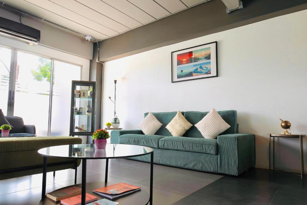 A bright lounge with a green sofa, coffee table and glass doors.