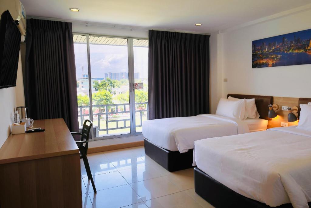 A twin room with two beds, a full-width work desk, and a glazed balcony opening.
