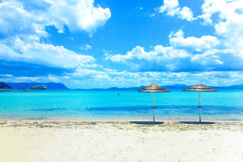 due ombrelloni seduti su una spiaggia con l'oceano di Appartamenti Ortensia Golfo Aranci a Golfo Aranci