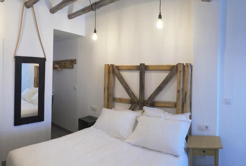 a bedroom with a bed with white pillows and a mirror at Hostal Gargal in Olvega