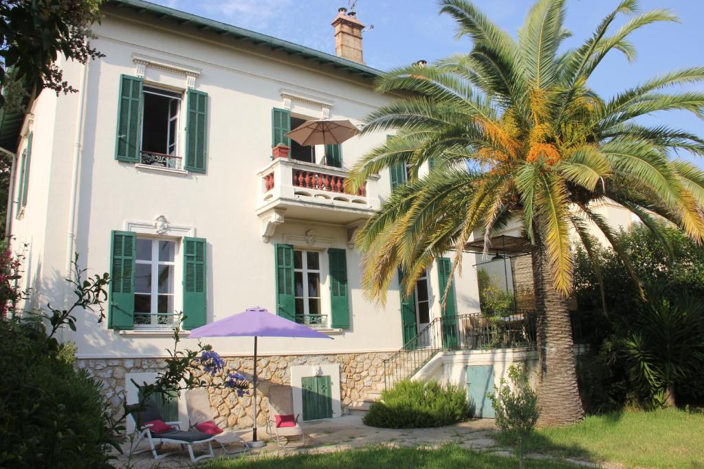 a house with a palm tree in front of it at Villa Cottage Reine, RC Jardin in Cannes