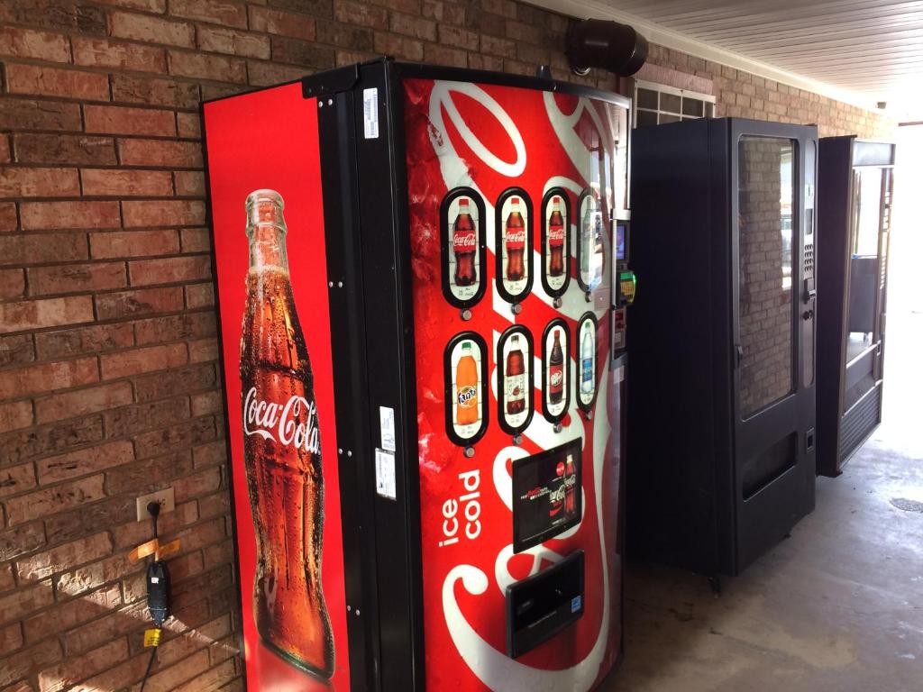 a cocacola soda machine next to a brick wall at Travel Inn & Suites in Atlanta