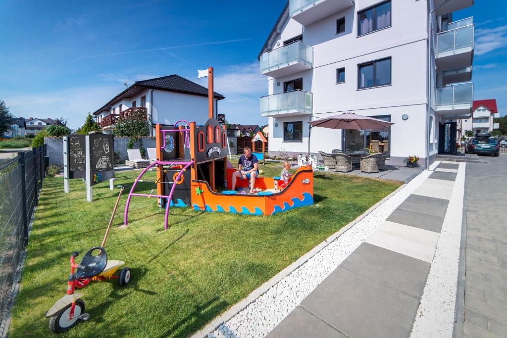 un niño jugando en un patio de juegos frente a un edificio en Willa Port, en Karwia