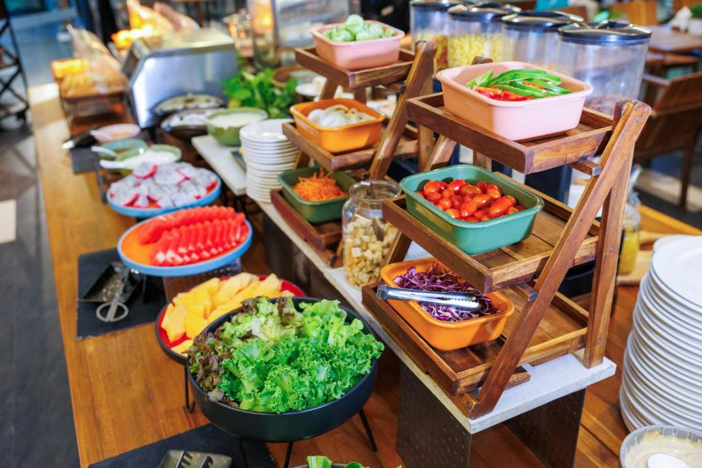 A long buffet station with bowls of salad, fruit, vegetables and condiments.