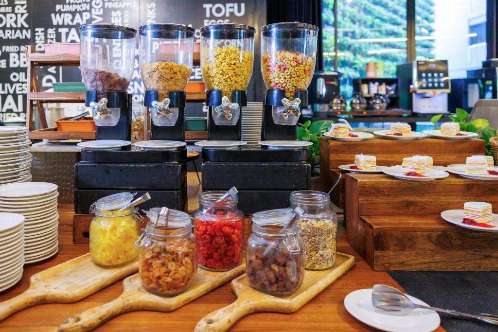 A buffet station with cereal dispensers, jars of toppings and plated food.
