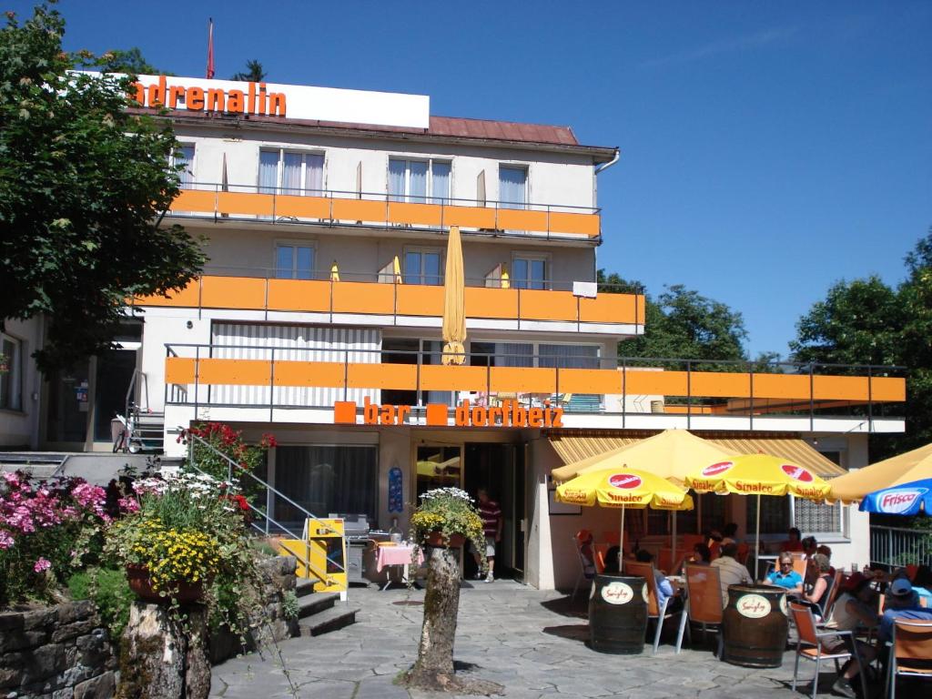 Un bâtiment avec des personnes assises à l'extérieur dans l'établissement Adrenalin Backpackers Hostel, à Braunwald