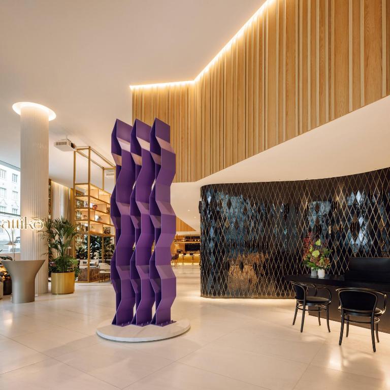 The lobby pairs a large purple geometric sculpture with a softly lit reception and lounge area.