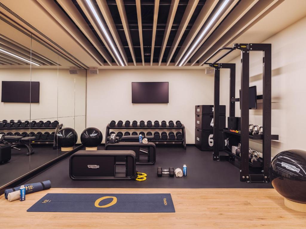 A compact, well-equipped gym offers cardio, free weights, a rack, mats, and mirrored walls.