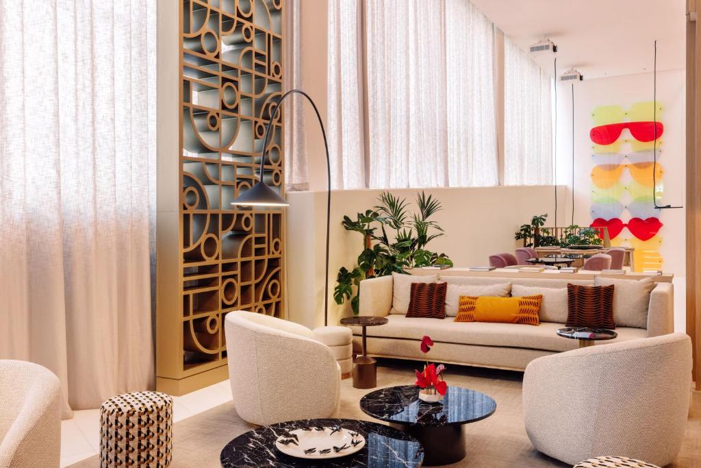 A plush lounge offers generous sofas, armchairs, marble tables, and tall curtained windows.