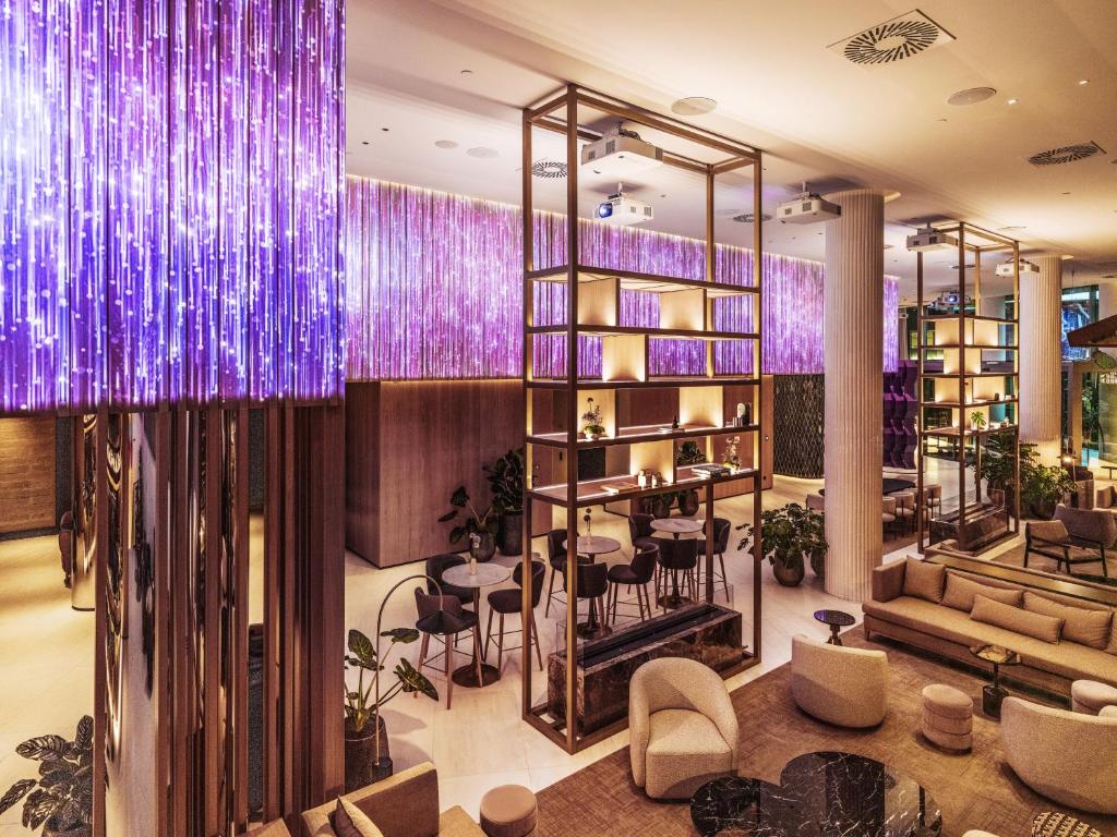 A richly lit lobby lounge with purple illumination, shelving, and low seating.