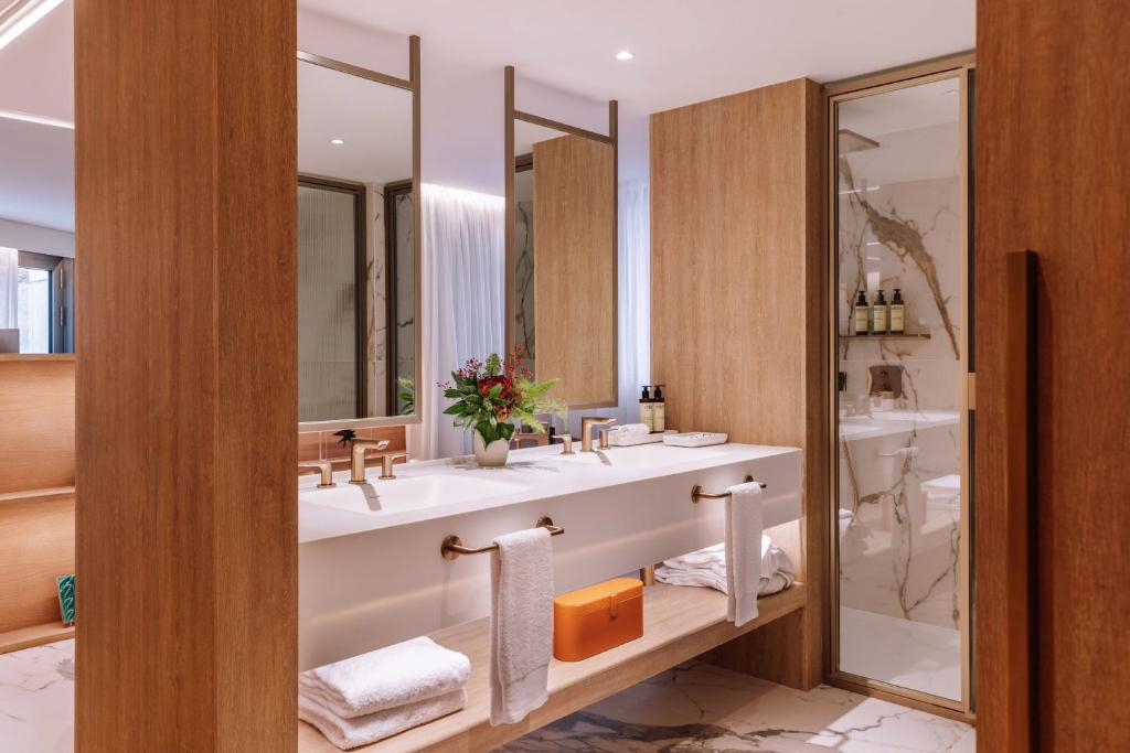A marble-finished bathroom with a double vanity and separate glass shower.