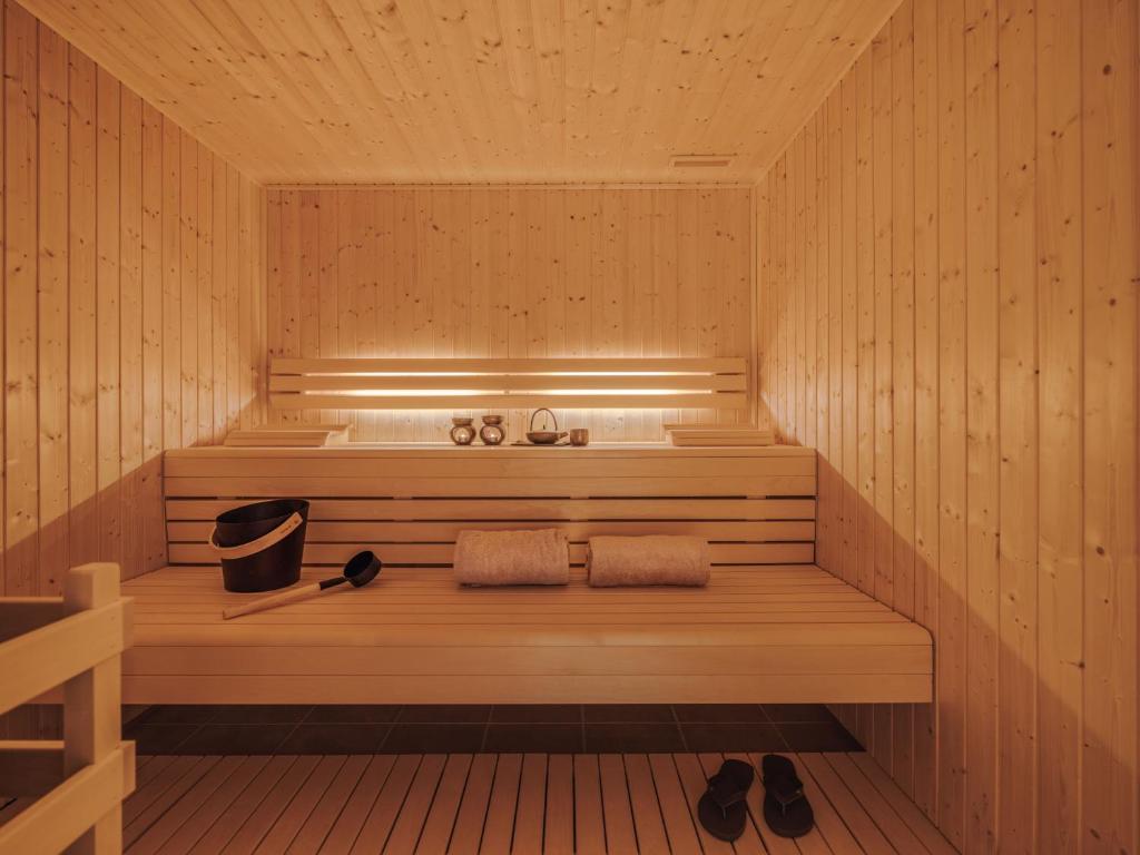 A compact cedar sauna with tiered benches, towels, a bucket, and ladle.