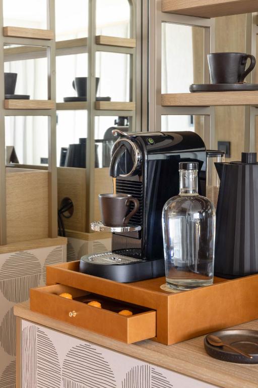 A polished coffee setup with a pod machine, kettle, cups and bottled water.