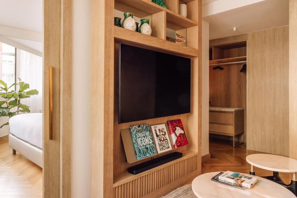 A built-in media wall and open wardrobe sit beside a compact seating area.