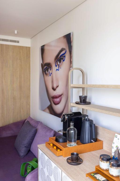 A compact hotel sitting area with a beverage station and statement portrait.