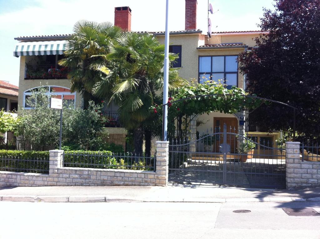 a house with a palm tree in front of a fence at Apartments Boris in Poreč
