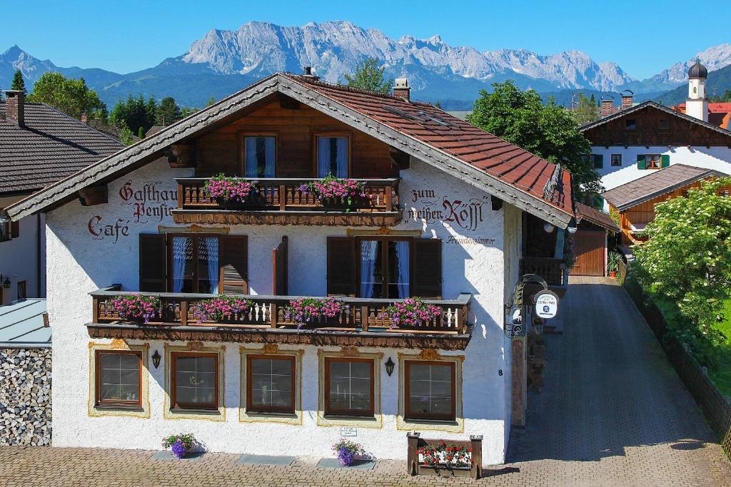 ein Gebäude mit einem Balkon mit Blumen darauf in der Unterkunft Frühstückspension Gästehaus Zum weissen Rössl in Wallgau