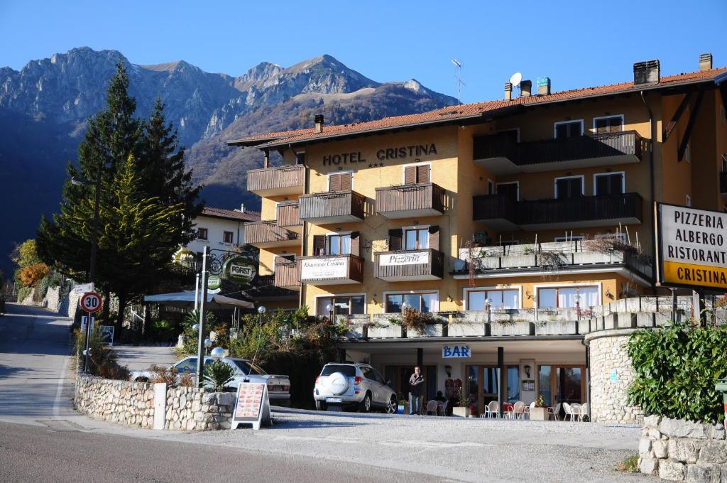 a hotel on a street with mountains in the background at Hotel Cristina in Tenno