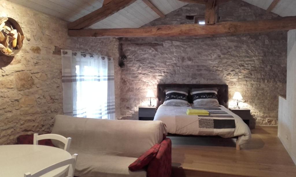 ein Schlafzimmer mit einem Bett und einem Sofa in einem Zimmer in der Unterkunft Studio Du Cluzel in Pontcirq