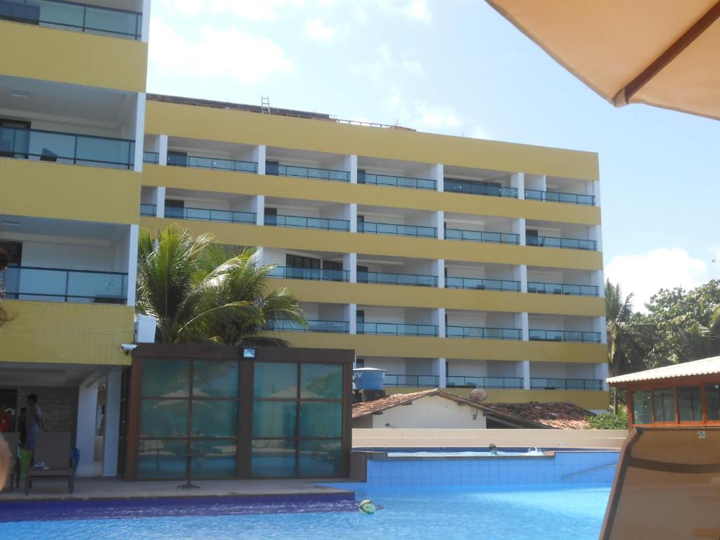 a building with a swimming pool in front of it at Tabatinga Residence Apart Hotel in Conde