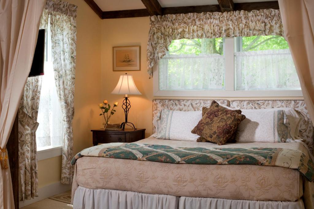 a bedroom with a bed and two windows at West Hill House B&B in Mad River Valley in Warren