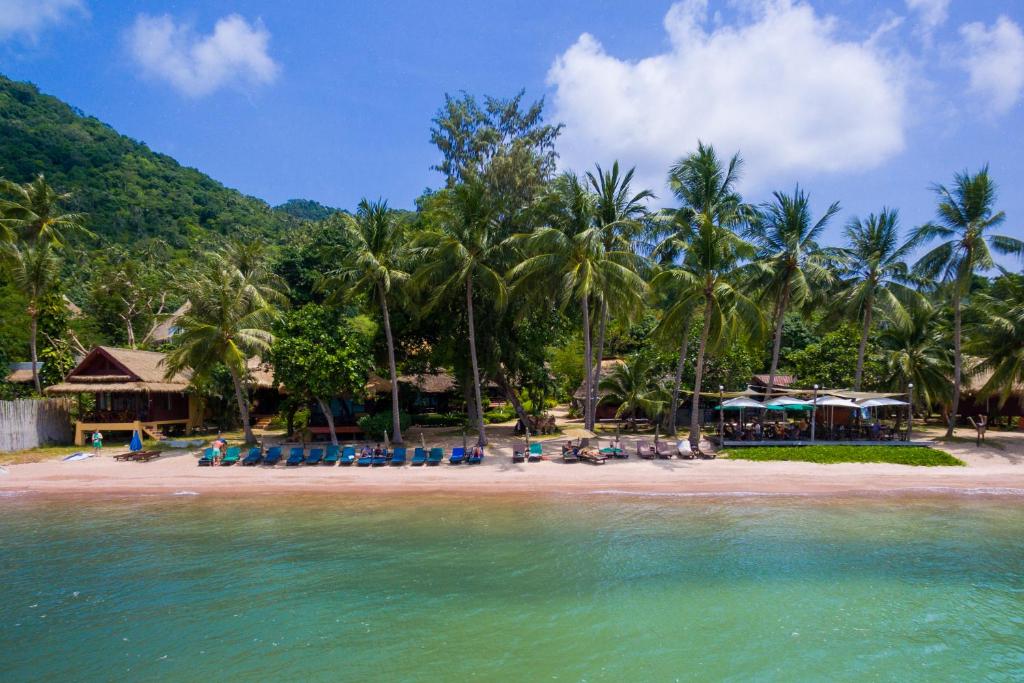 a beach with chairs and palm trees in the water at Palm Leaf Resort Koh Tao in Ko Tao