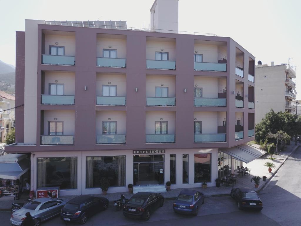 a pink building with cars parked in front of it at Ionion Hotel in Kyparissia