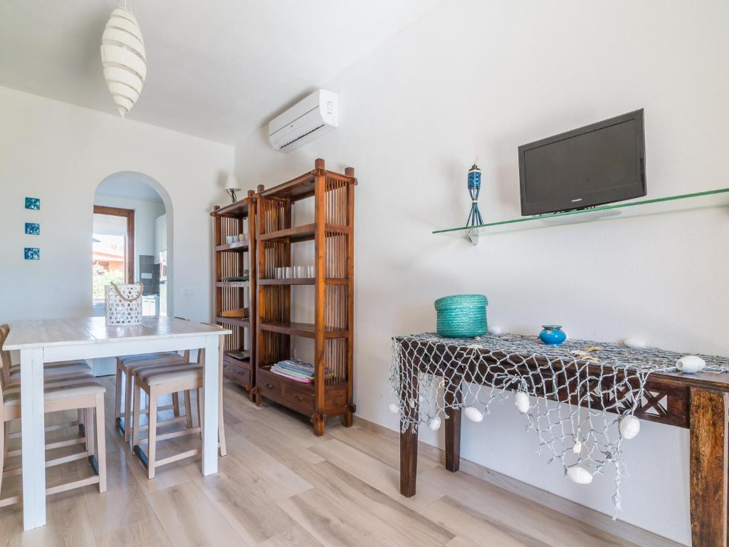 ein Wohnzimmer mit einem Tisch und einem TV an der Wand in der Unterkunft Prima fila Costa Rei in Costa Rei