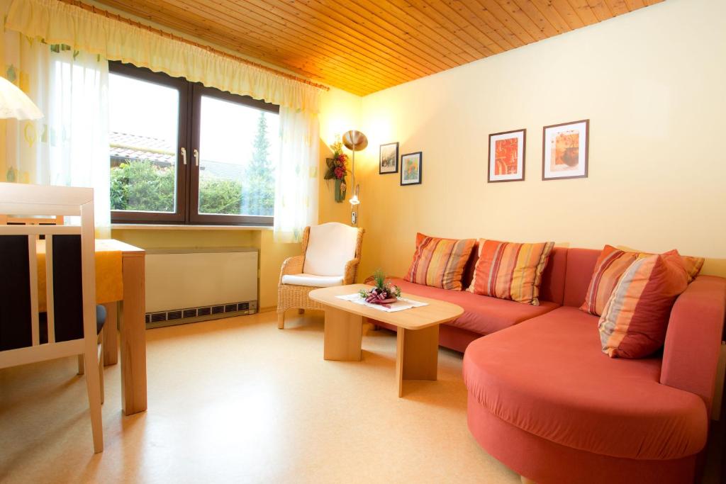 a living room with a red couch and a table at Ferienappartements mit Herz in Bischofsmais