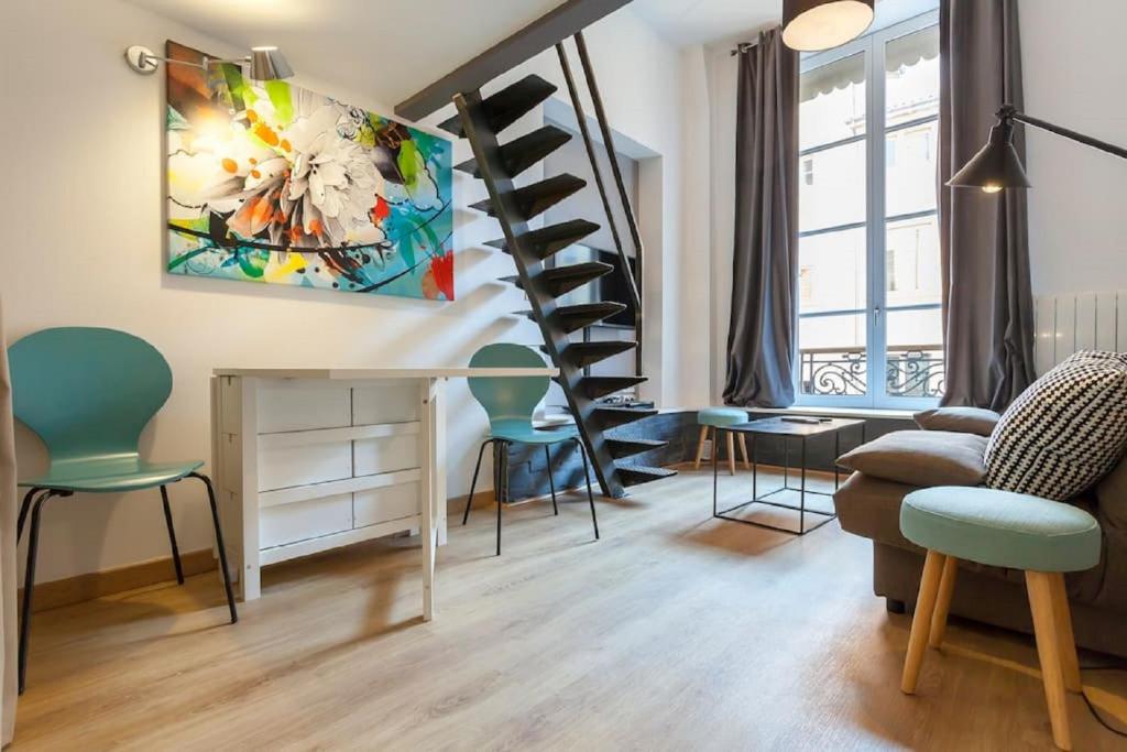 una sala de estar con sillas y una escalera de caracol en Appart Touriste, en Lyon