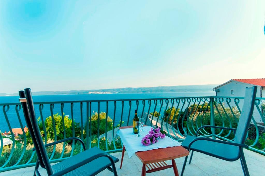 balkon z niebieskimi krzesłami i stołem z fioletowymi kwiatami w obiekcie Holiday Home Villa Marin w mieście Stanići