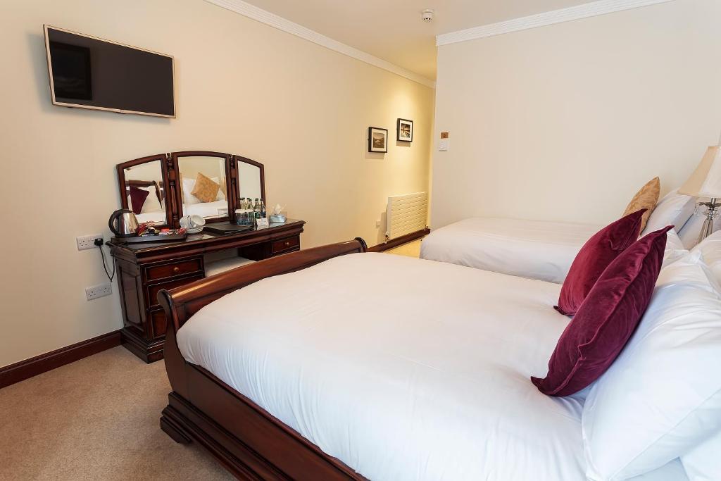 a hotel room with two beds and a mirror at Chester Beatty Inn in Ashford